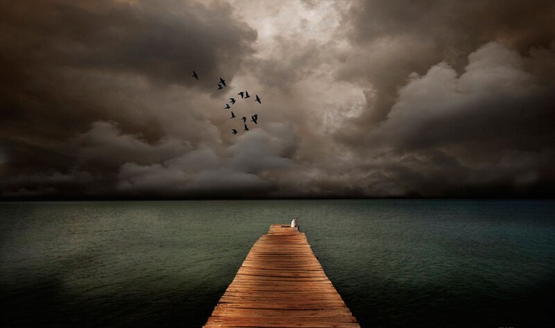 Person on a pier under stormy sky