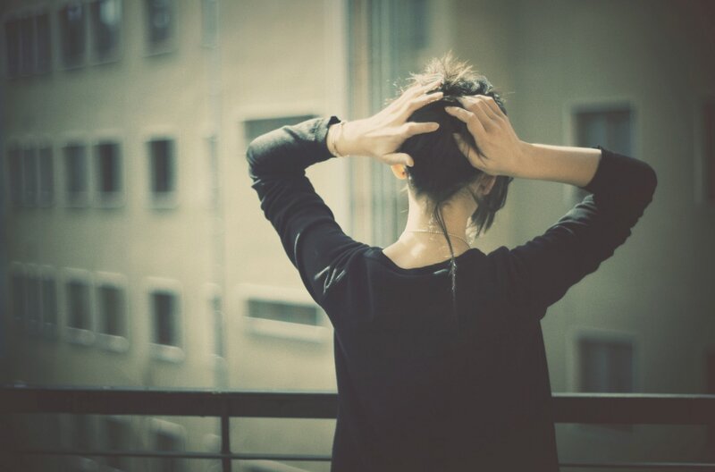 person on balcony with hands in hair