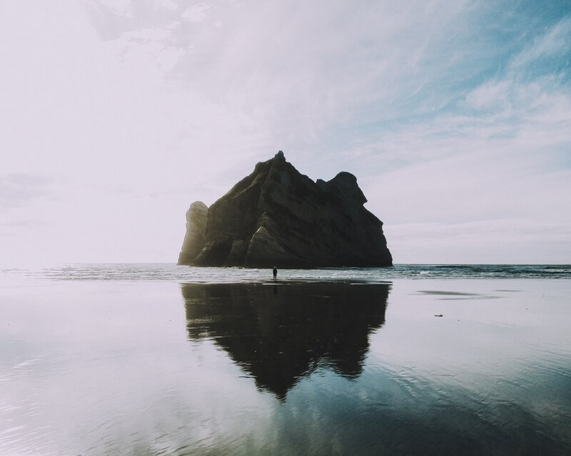 Person on Beach Near Rock