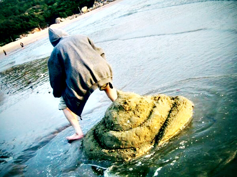 person on beach with sand sculpture