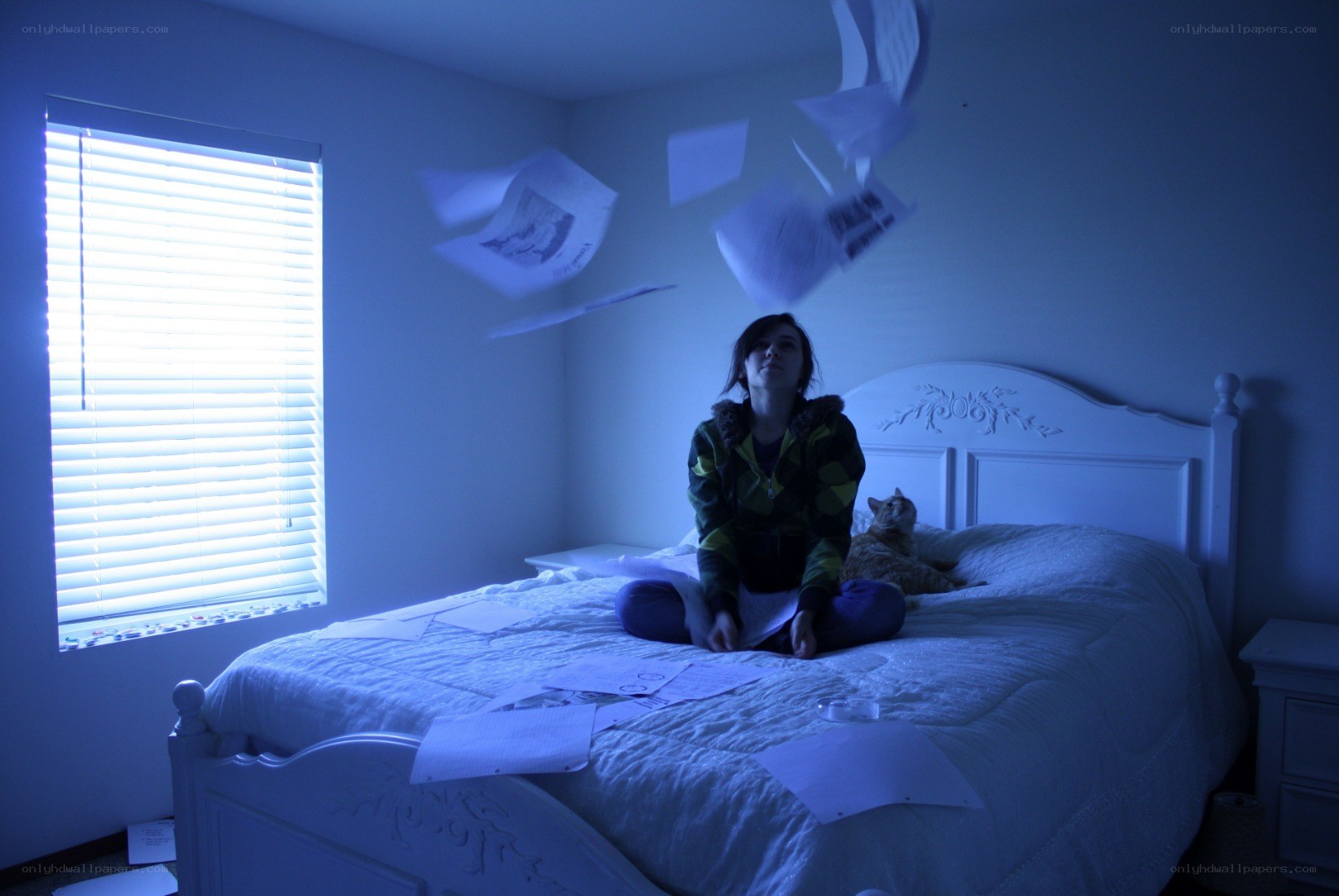 Person on bed with papers flying