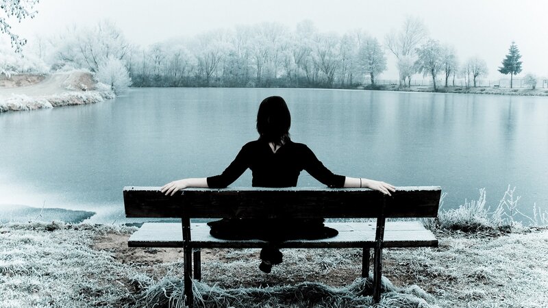 Person on bench by frozen lake