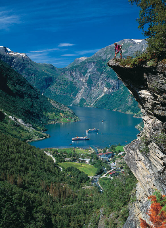 person on cliff overlooking fjord
