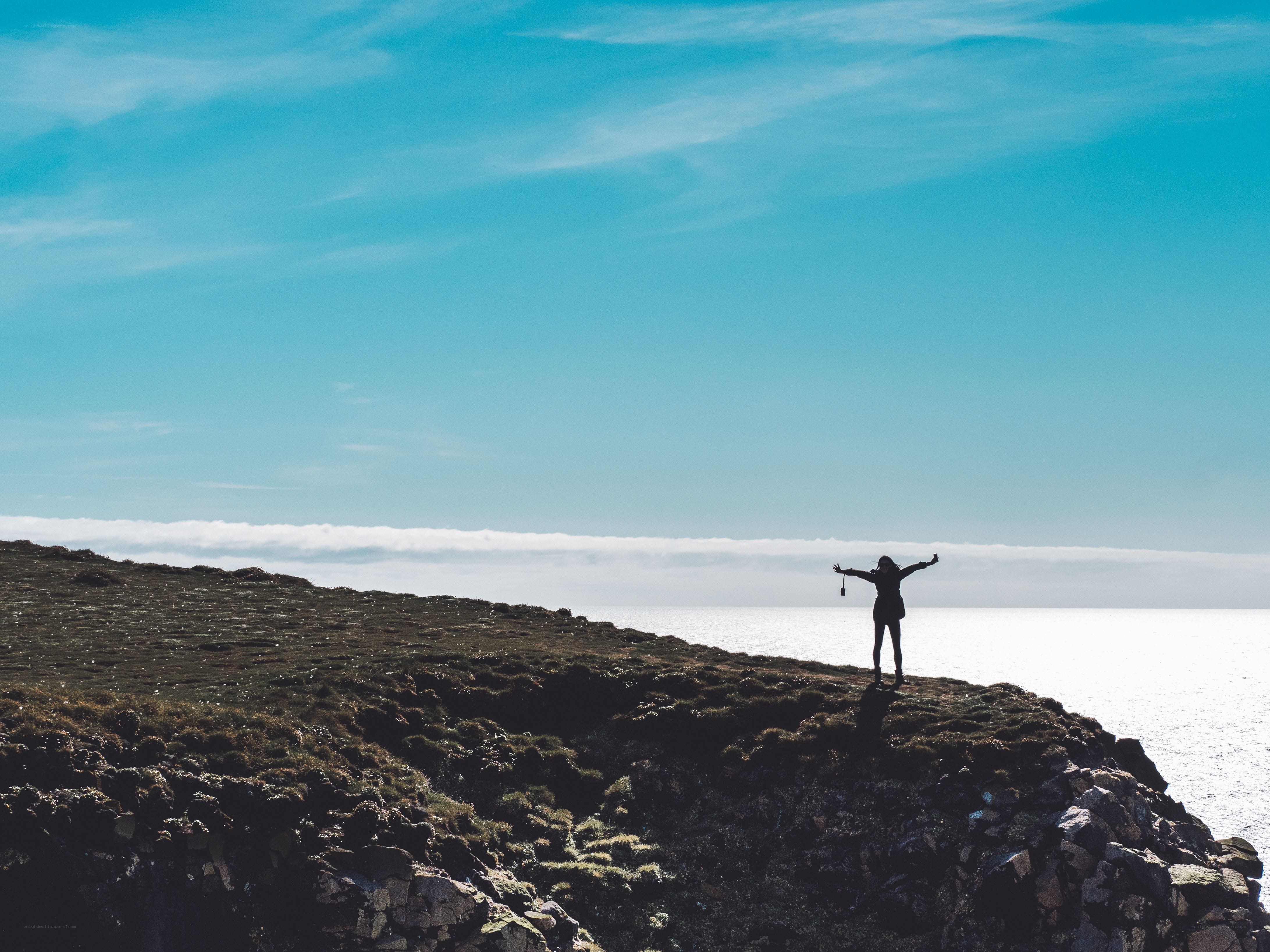 person on cliff overlooking sea