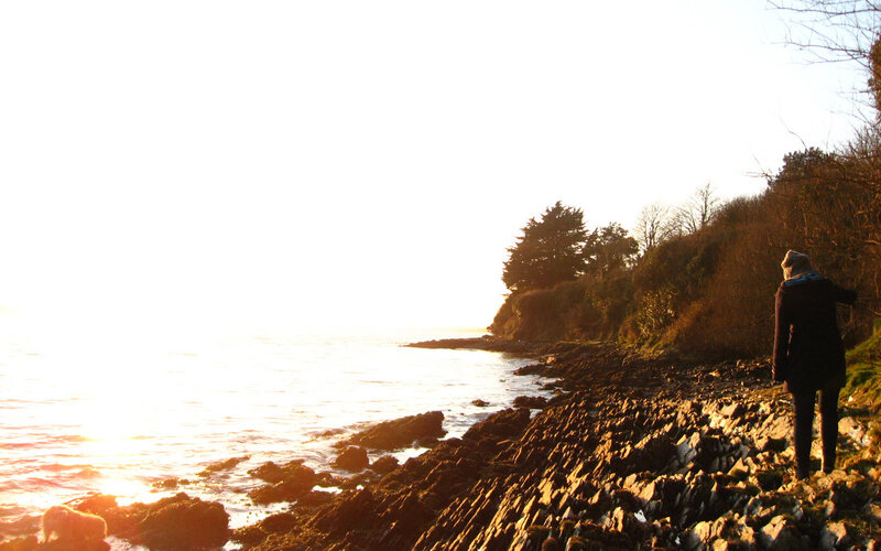 person on rocky shore at sunset