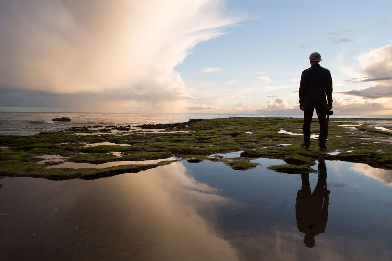 Person on Rocky Shore — Blue, Serene, Sunset, Photograph, Ocean