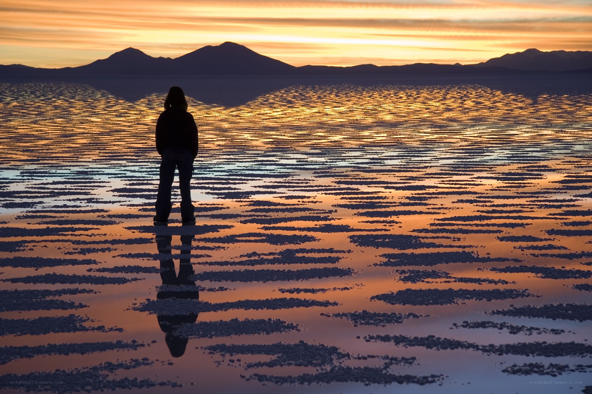 Person on salt flats at sunset