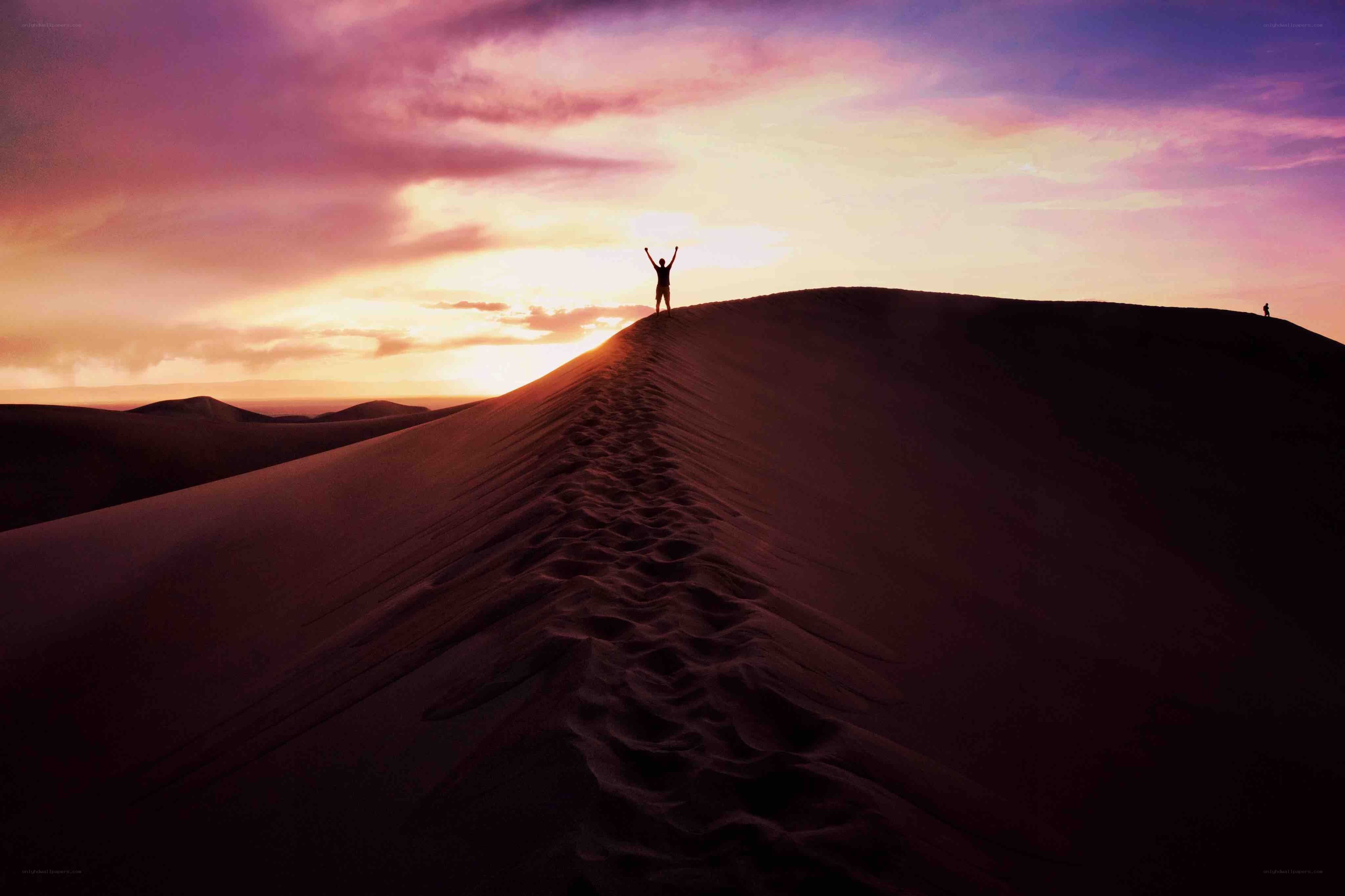 Person on sand dune at sunset