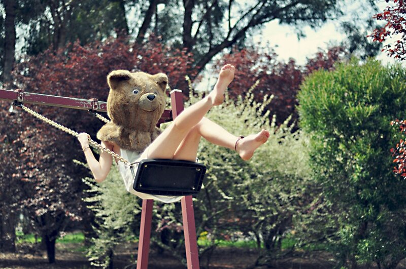 person on swing with teddy bear head