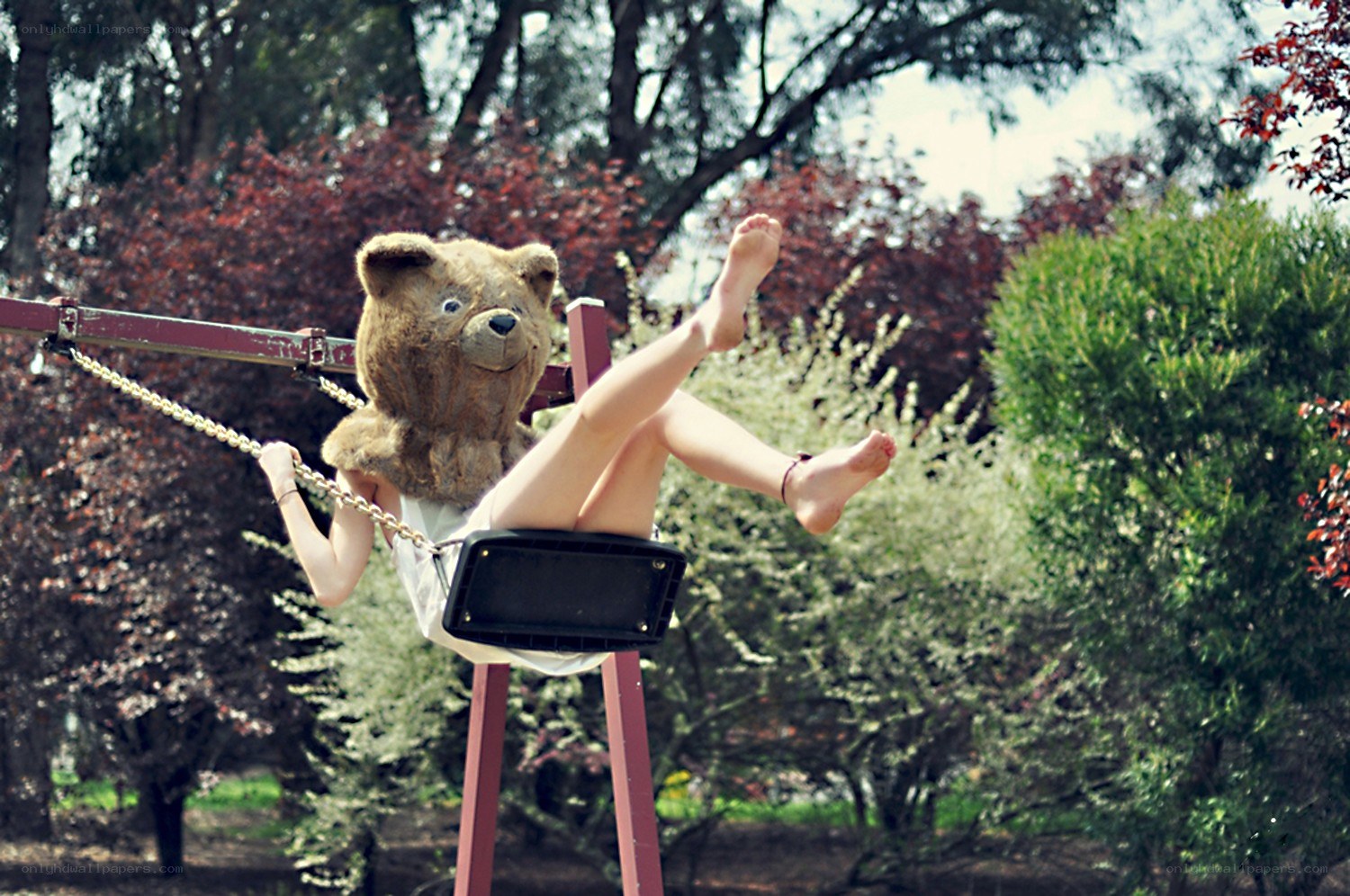 person on swing with teddy bear head