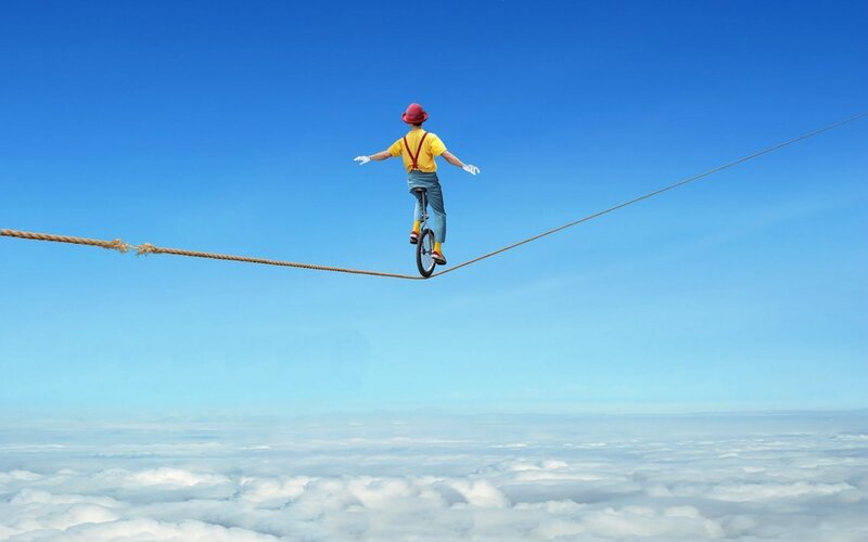 Person on unicycle over clouds