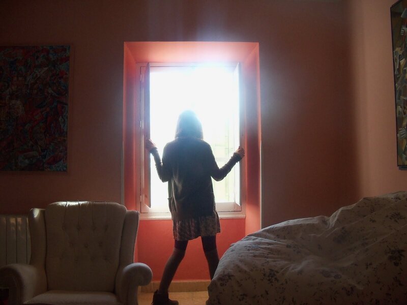person opening window at sunrise
