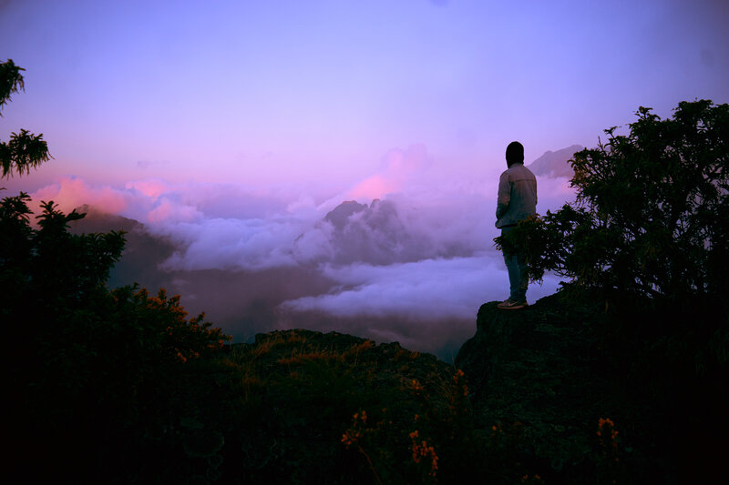Person overlooking clouds at dusk