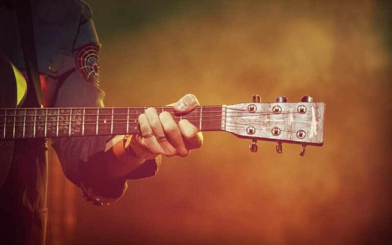 Person Playing Acoustic Guitar — Orange