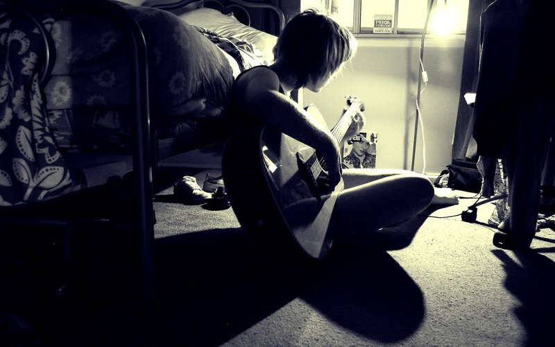 person playing guitar in bedroom