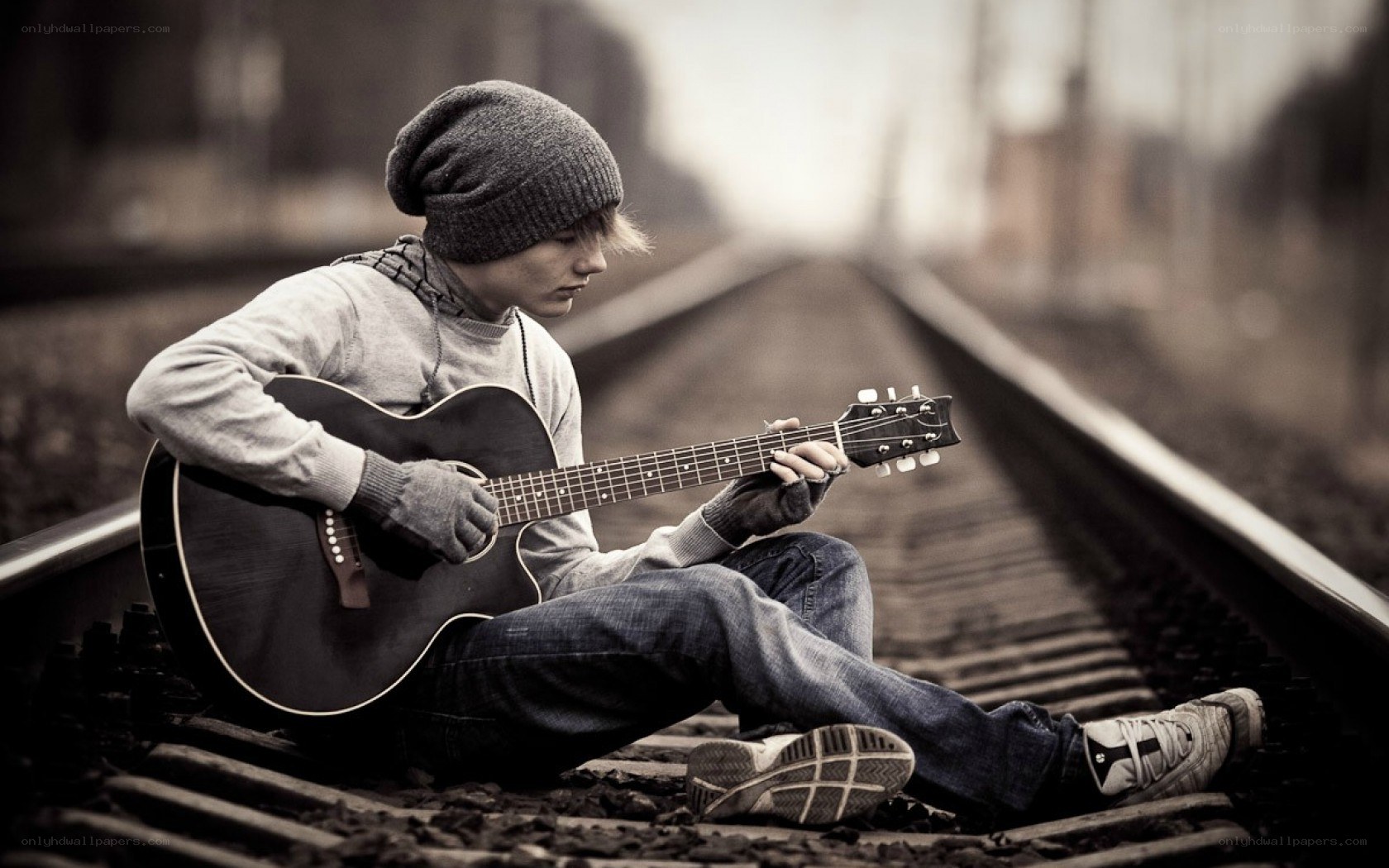 person playing guitar on train tracks