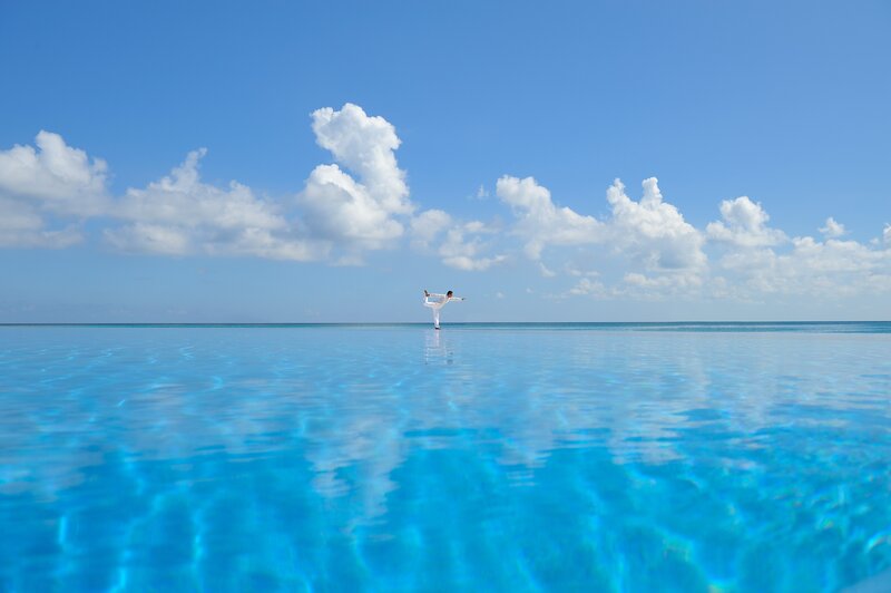 Person practicing yoga on infinity pool