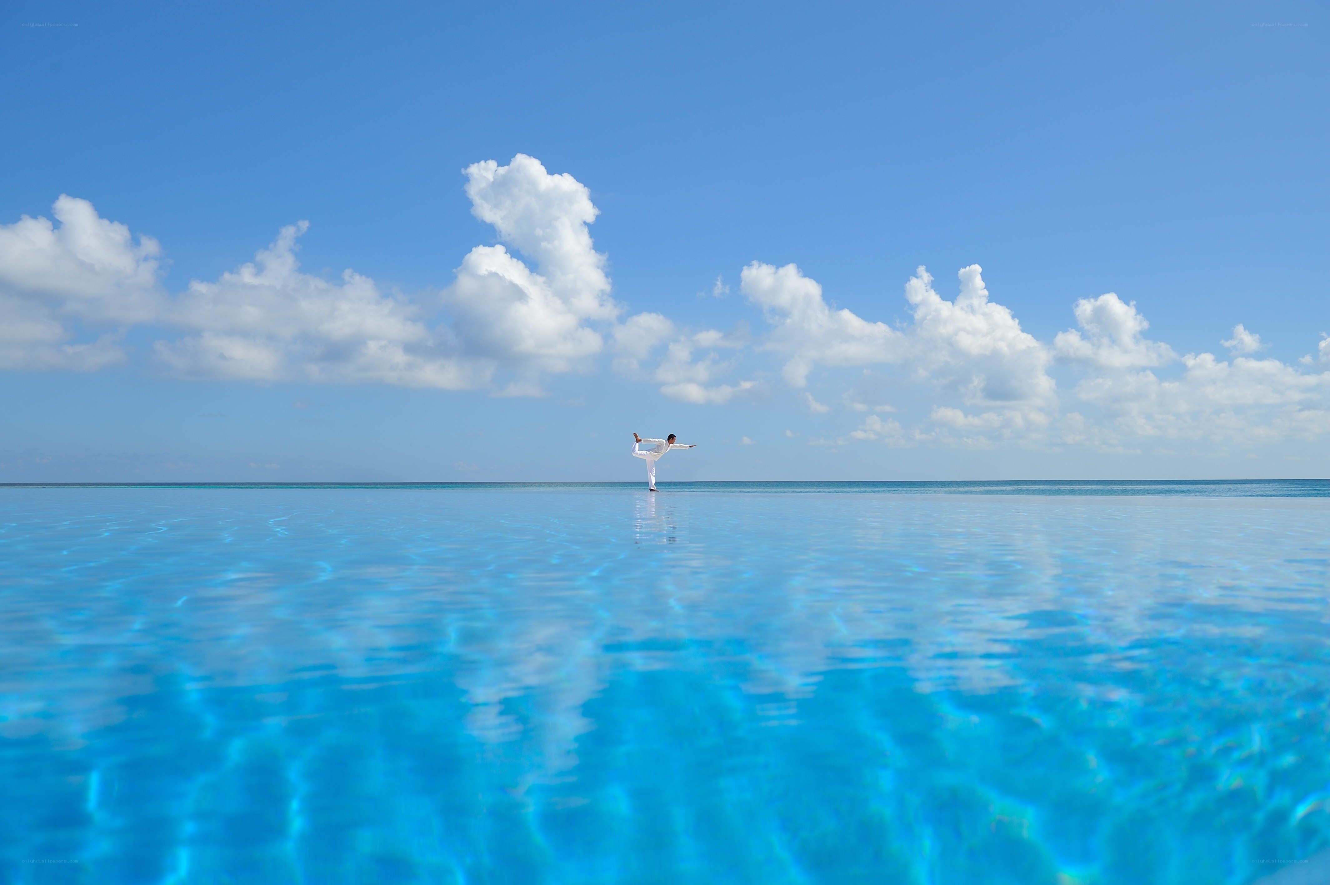 Person practicing yoga on infinity pool