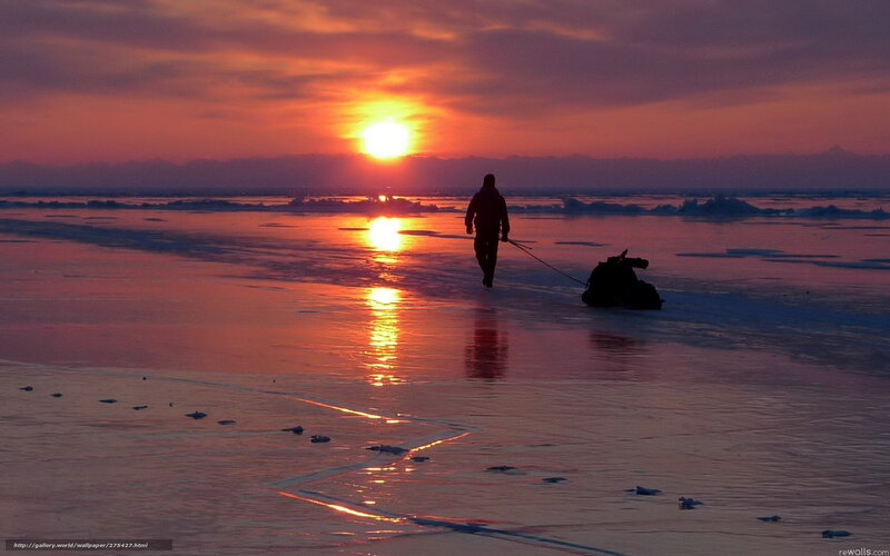Person pulling sled at sunset