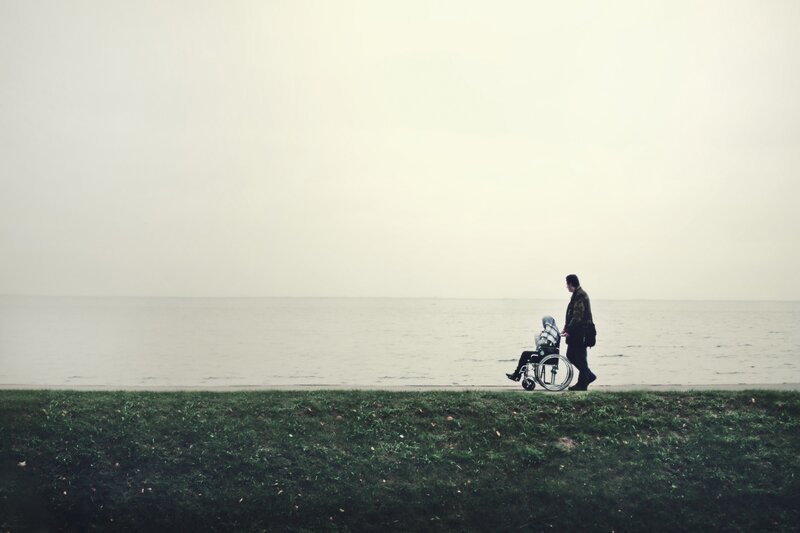 person pushing wheelchair by water
