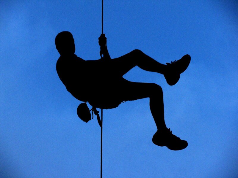 person rappelling against blue sky