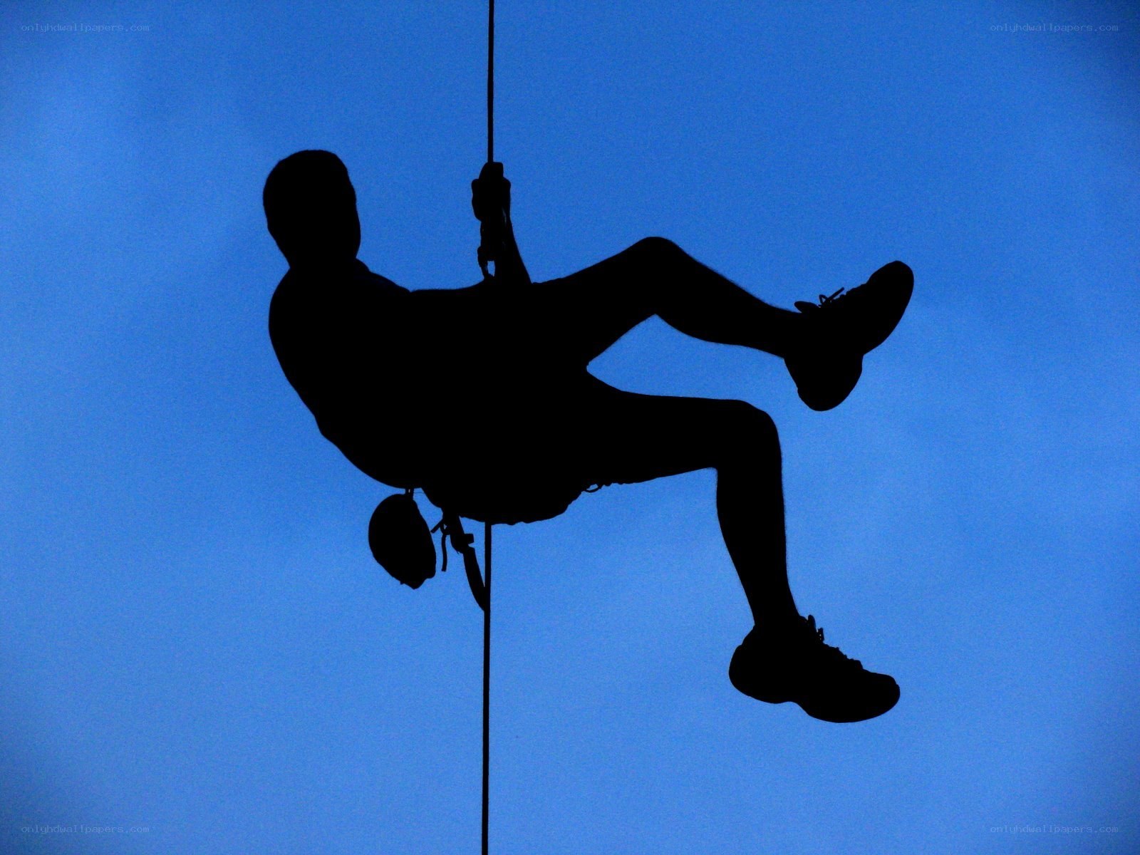 person rappelling against blue sky