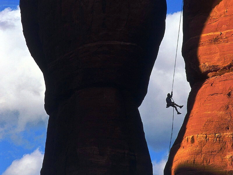 Person Rappelling Between Rocks