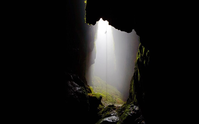 Person Rappelling in Cave — Black, Dramatic, Photograph, Light