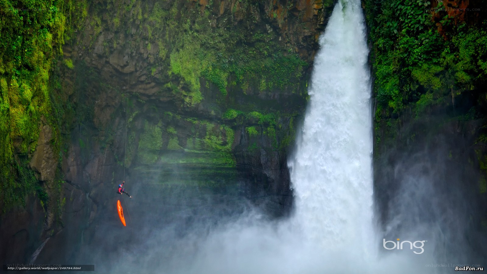 person rappelling near waterfall