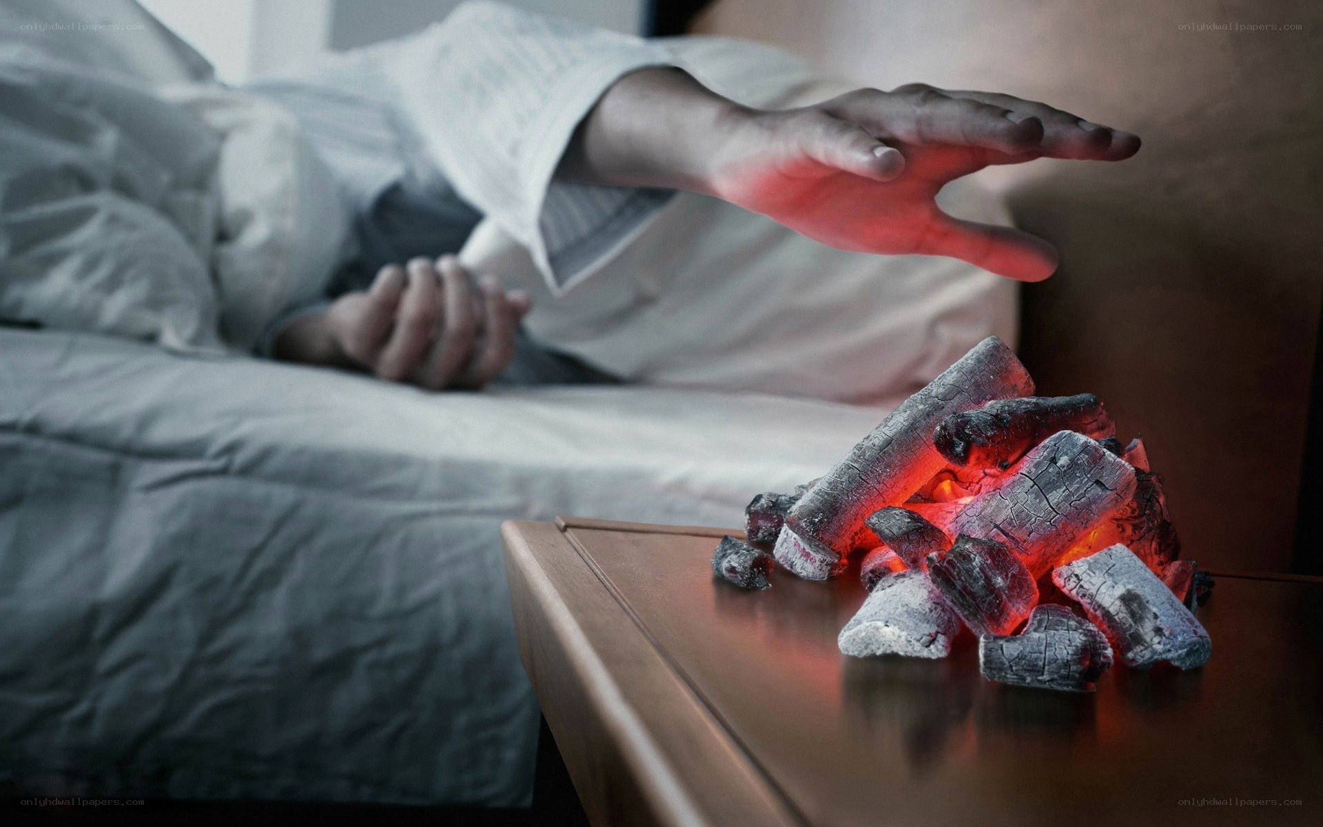 person reaching for glowing coals