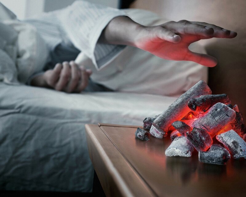 Person reaching for glowing coals