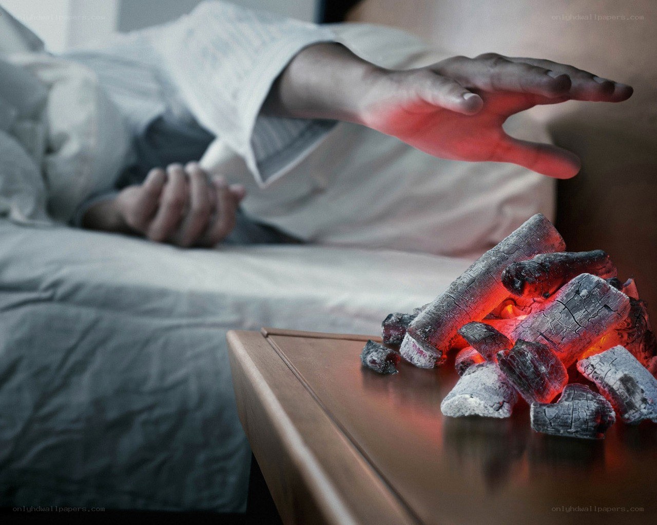 Person reaching for glowing coals