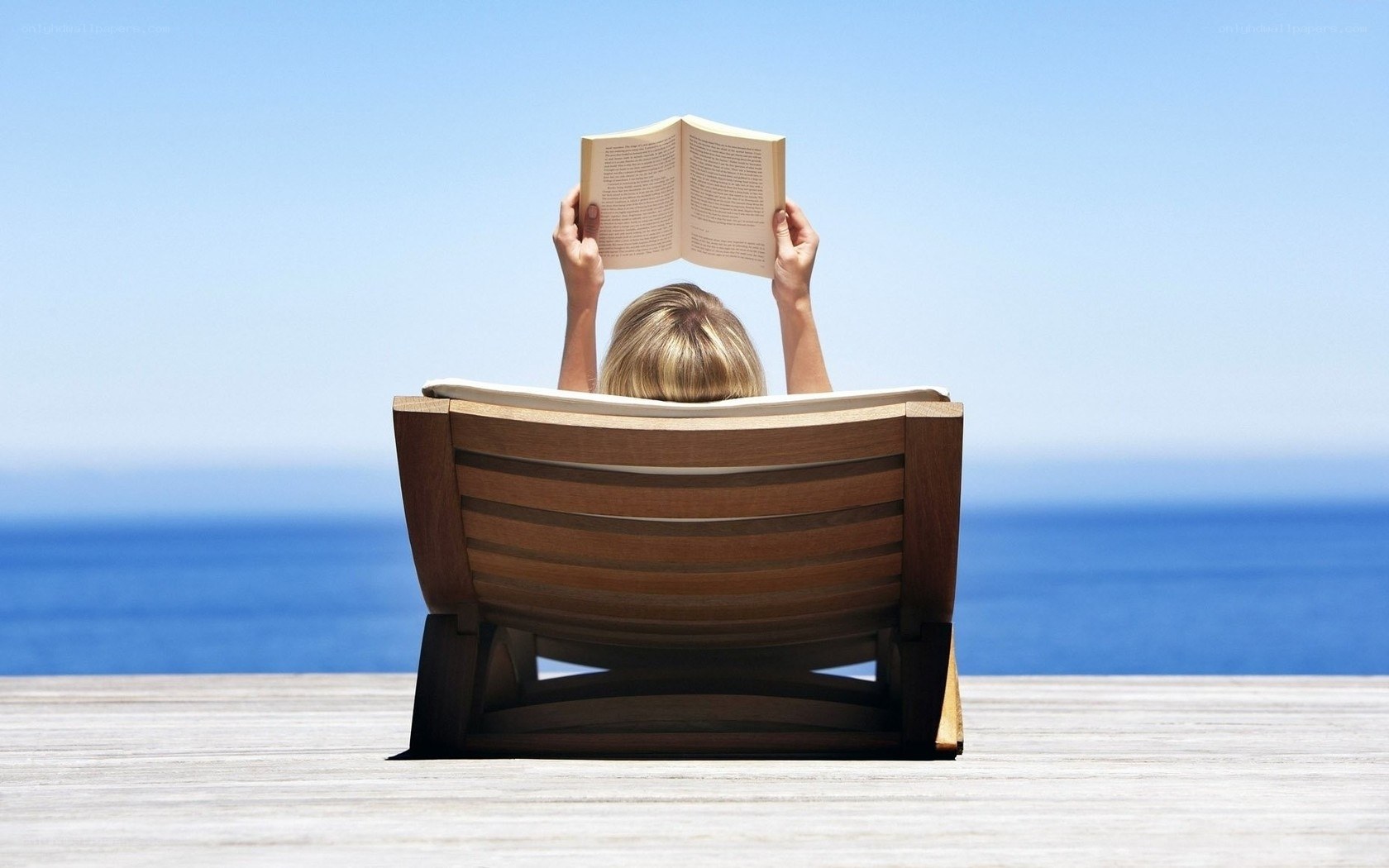 Person reading book by the sea