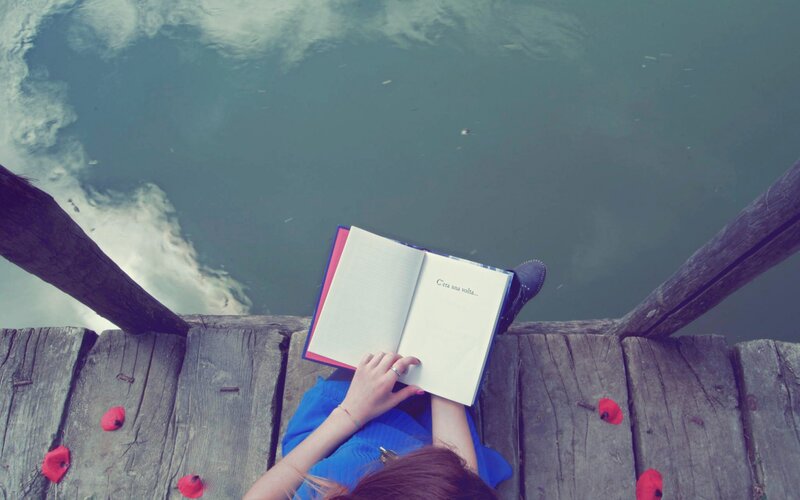 Person Reading Book on Dock