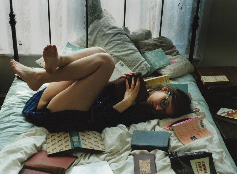 Person reading on a bed with books