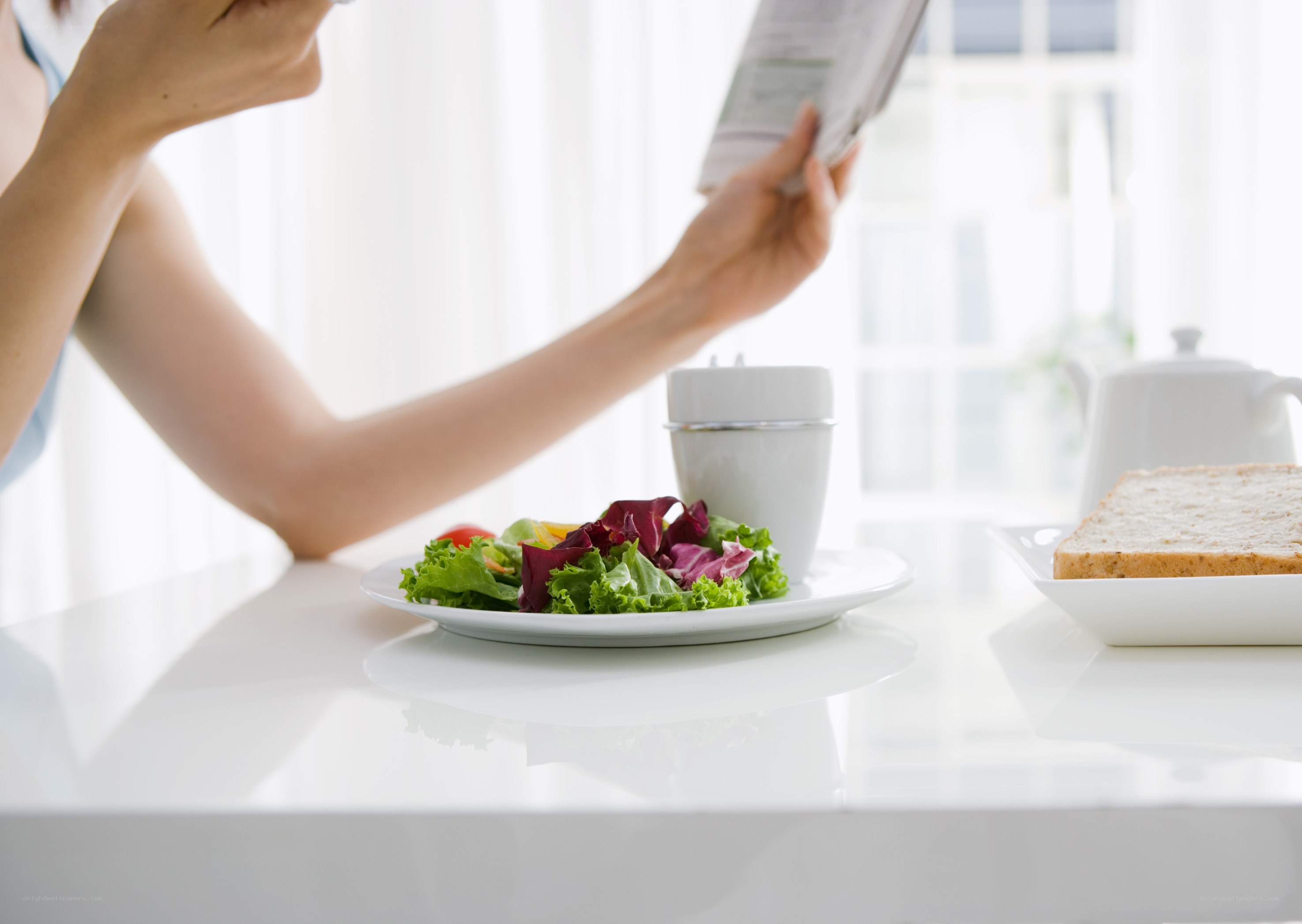 Person reading with salad at table