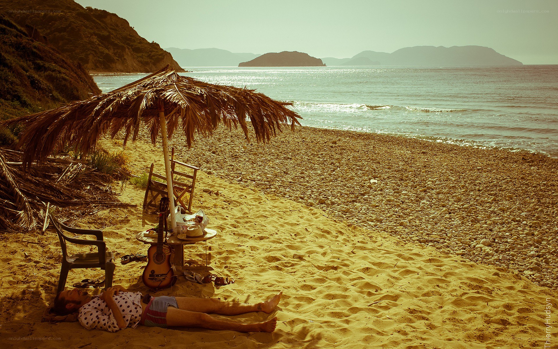 Person resting on a pebble beach