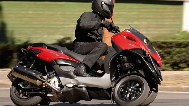 person riding red three-wheeled scooter