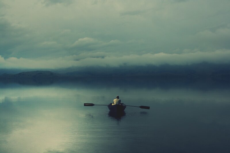 person rowing a boat on calm water