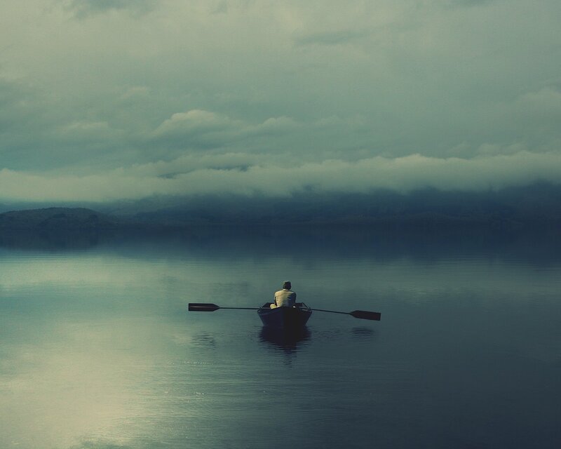 Person rowing boat on calm lake