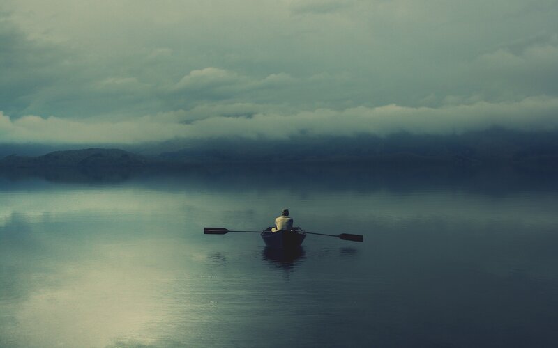 person rowing boat on calm lake