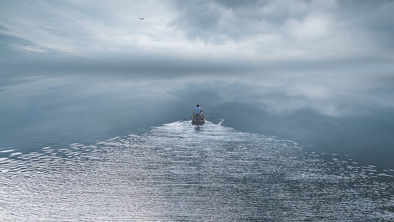 Person rowing boat on calm water