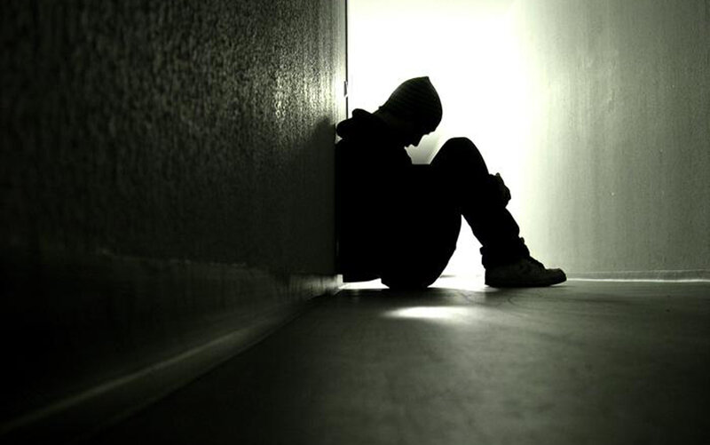 person sitting in a dark hallway
