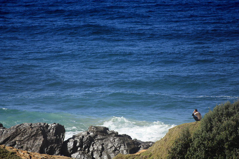 Person sitting on a cliff by the ocean
