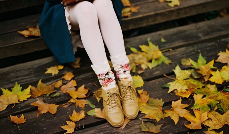 person sitting on bench with autumn leaves