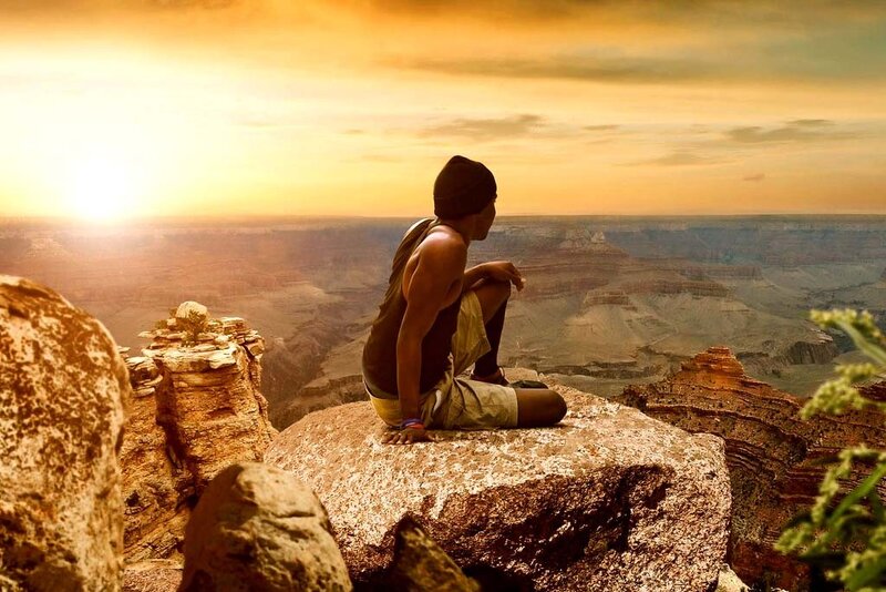 person sitting on cliff at sunset