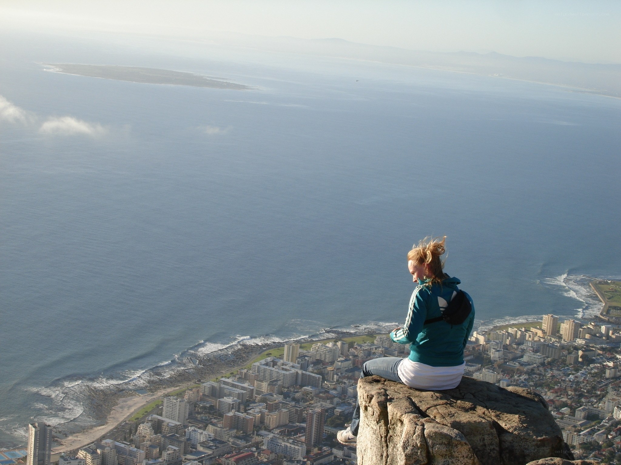 person sitting on cliff overlooking city