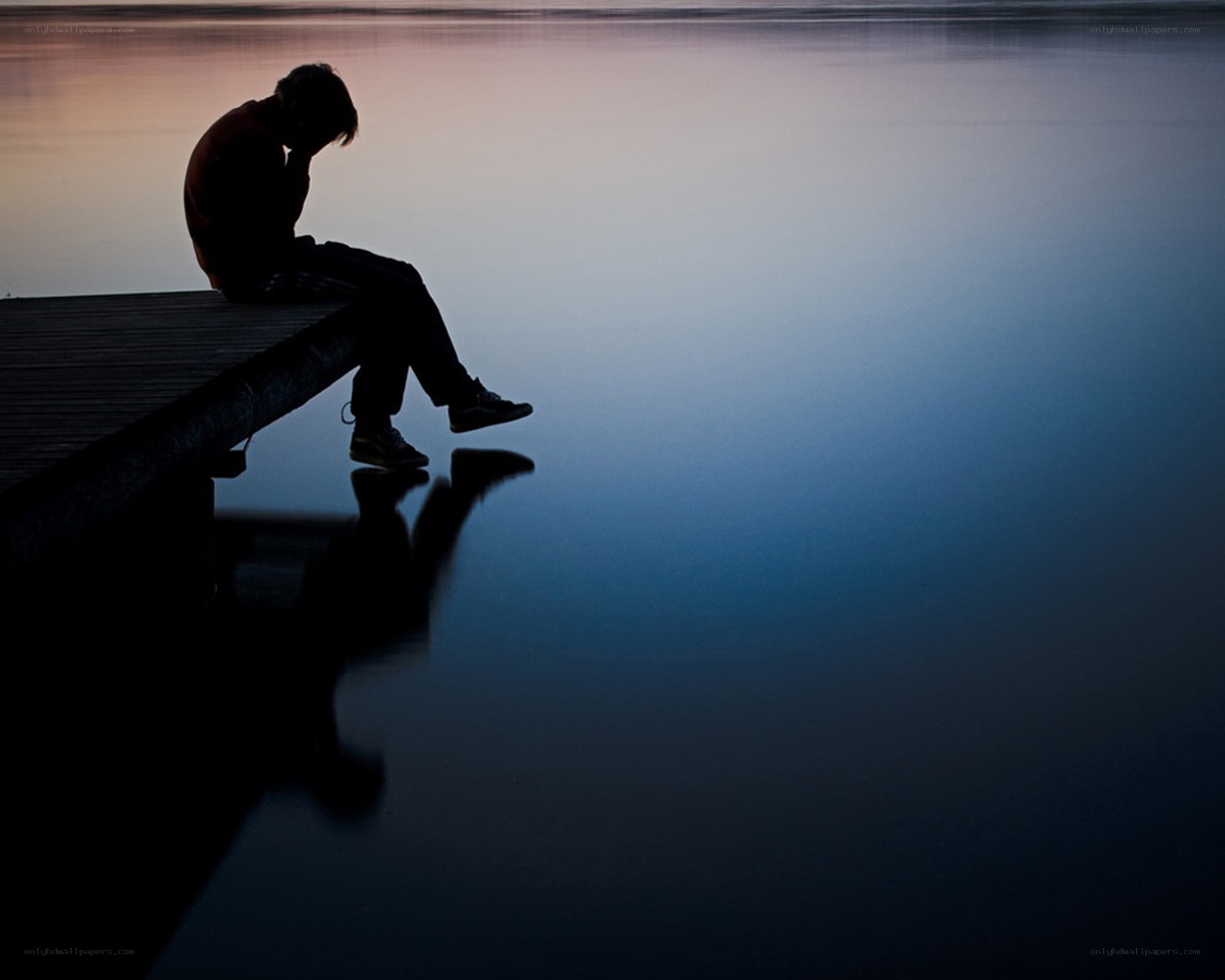 person sitting on dock at dusk