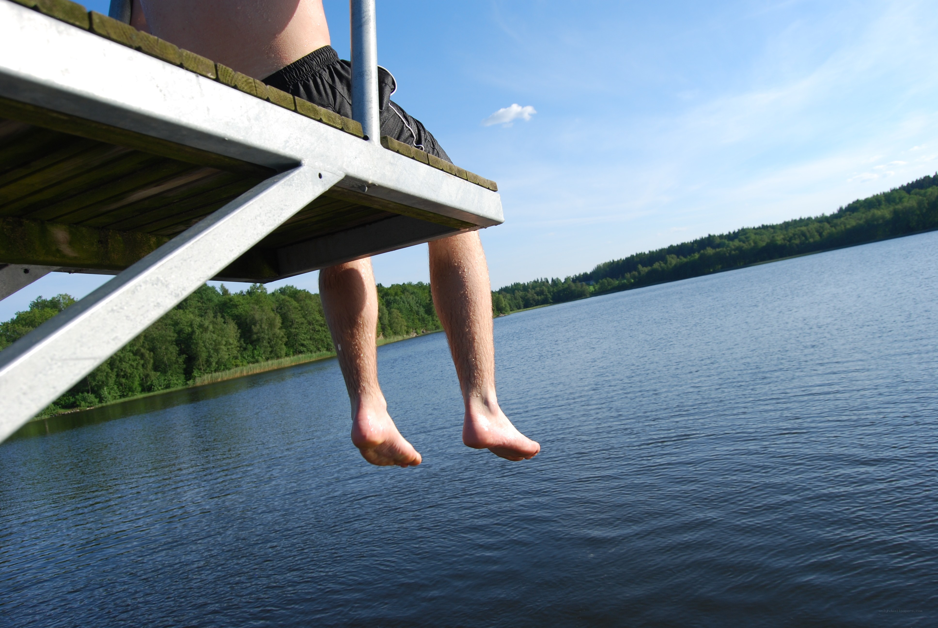 person sitting on dock by lake