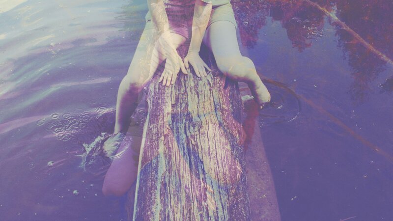 person sitting on log in water